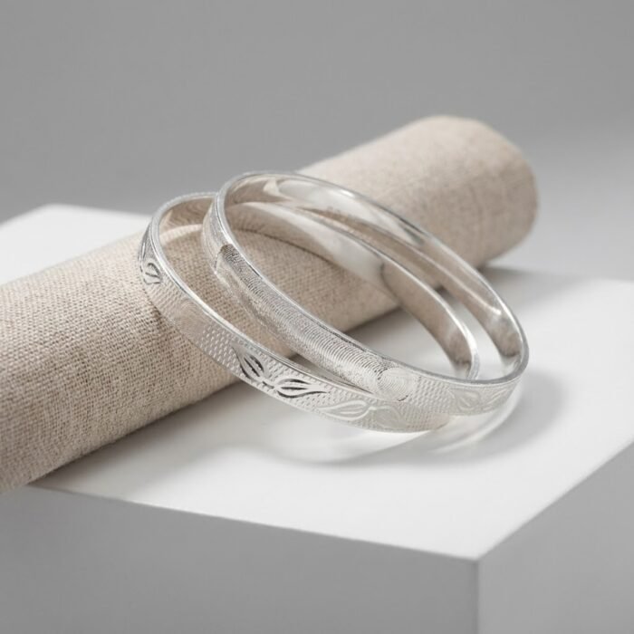 Minimal CNC silver bangles with precision engraved leaf pattern displayed on fabric roll – premium wholesale silver jewellery