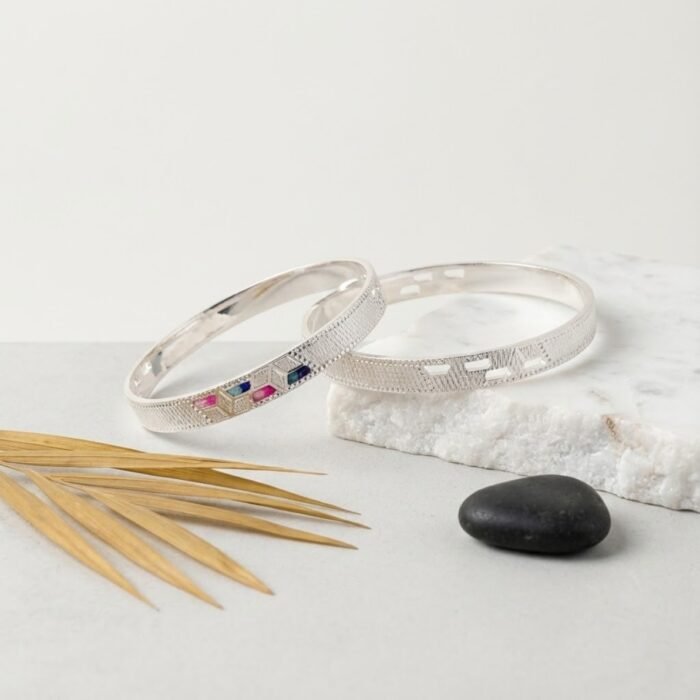 Pair of CNC geometric silver bangles with multicolour stones on marble background – wholesale designer silver bangles