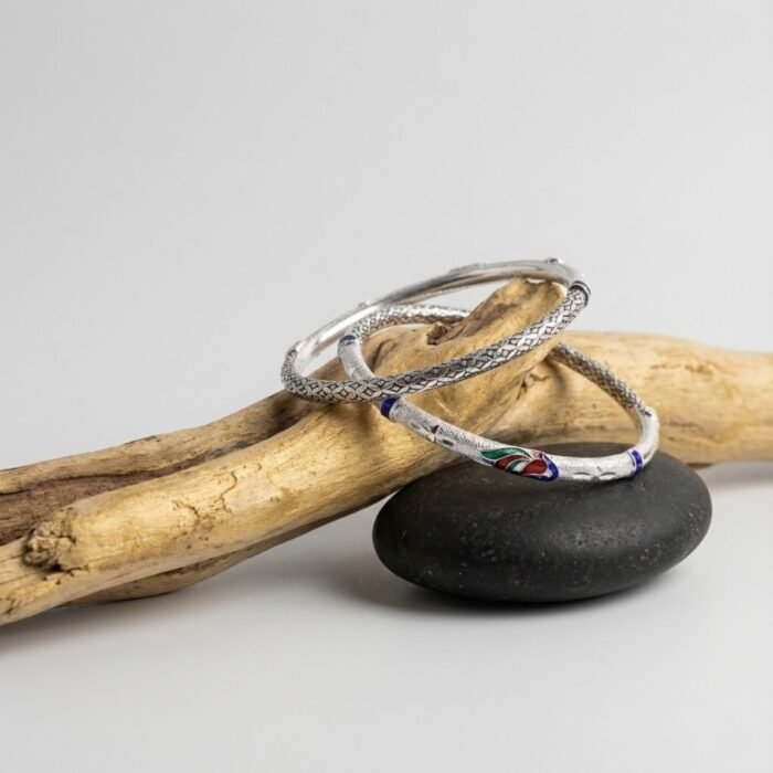 Lightweight hollow silver bangles with engraved design and enamel detailing displayed on wooden branch – premium women’s silver jewellery