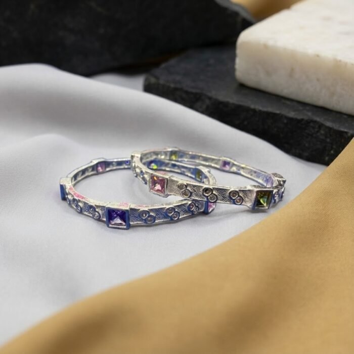 Semi micro silver baby bangle with pink square stone and engraved texture displayed on marble block – wholesale silver baby jewellery