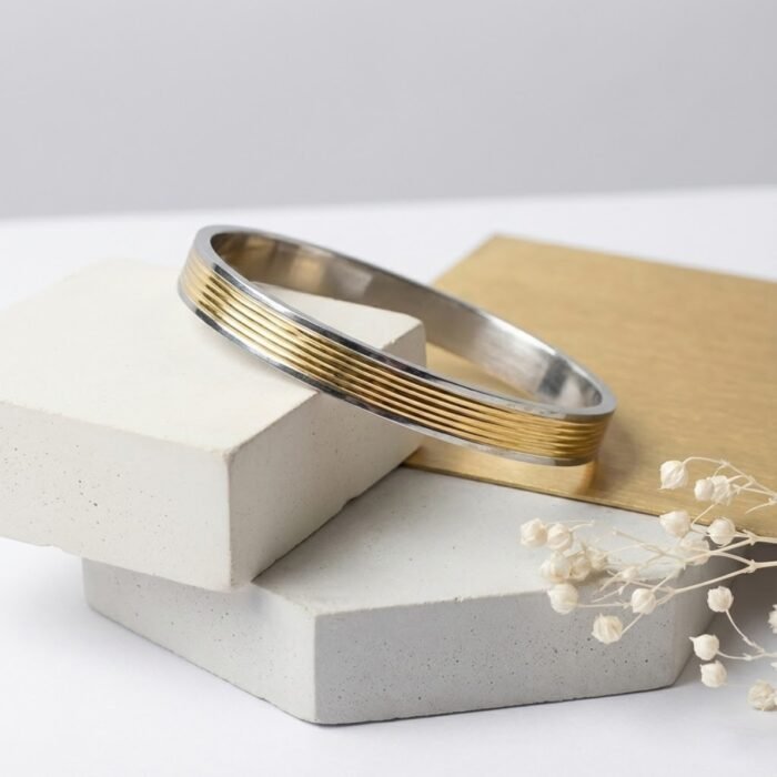 Two-tone men’s silver kada with gold lines displayed on geometric blocks – stylish gents kada jewellery