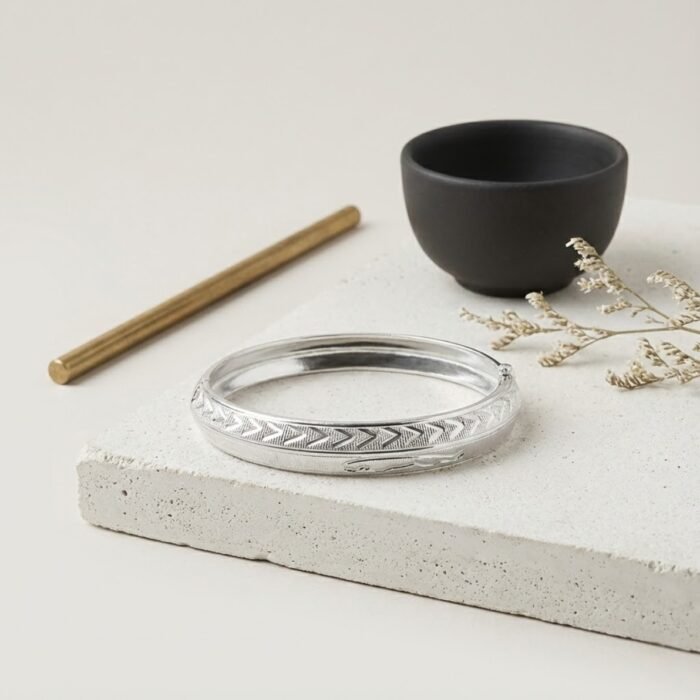 Premium engraved mens silver kada displayed on stone background